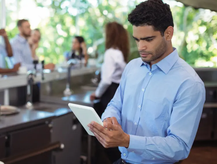 Teardrop Hotels waiter using a digital tablet outdoors